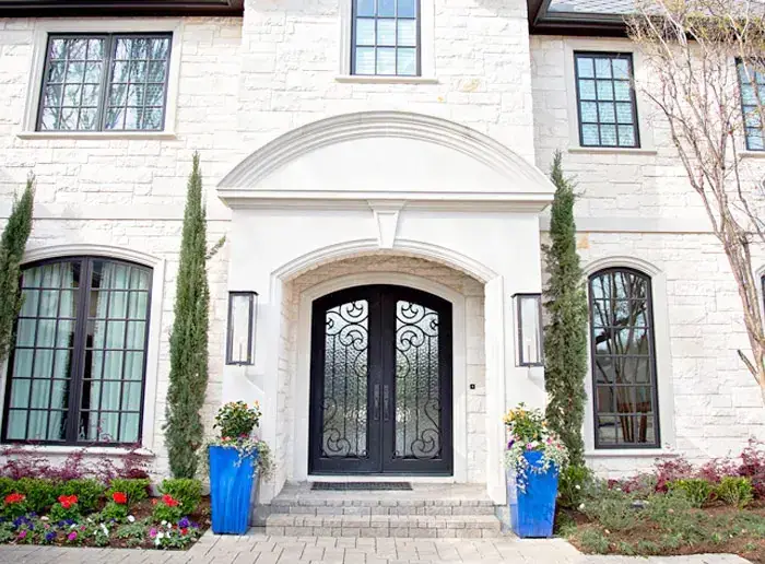 Arched wrought-iron double entry doors on a limestone home