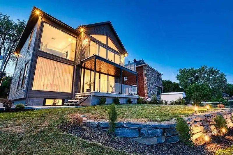Home at dusk with gable window wall and balcony glazing